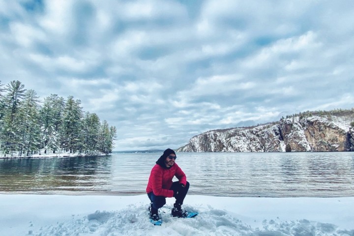 a man riding a snowboard down the side of a lake